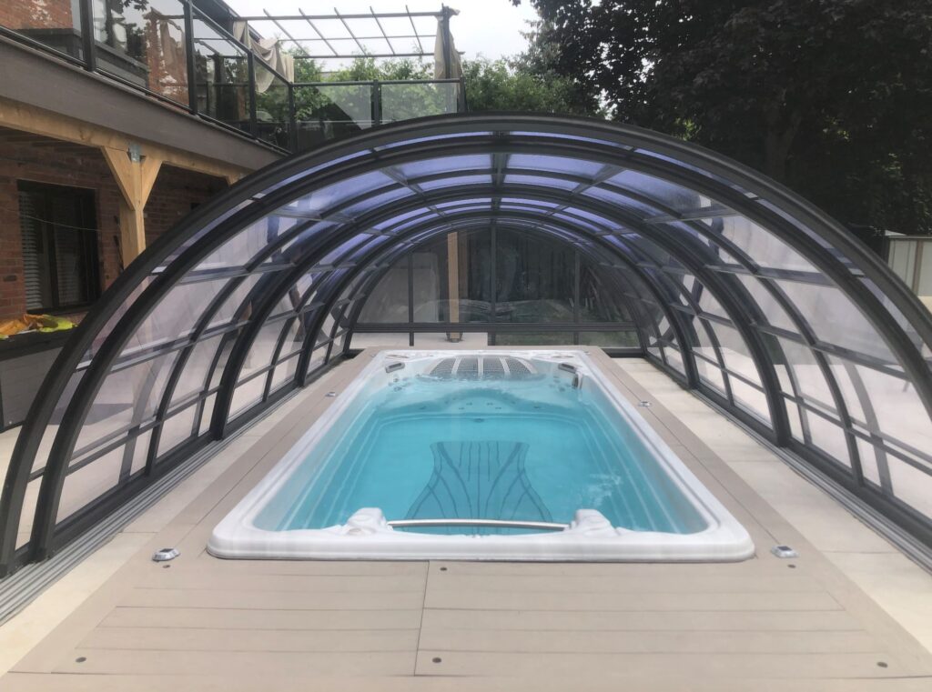 Retractable pool cover over rectangular outdoor hot tub on deck