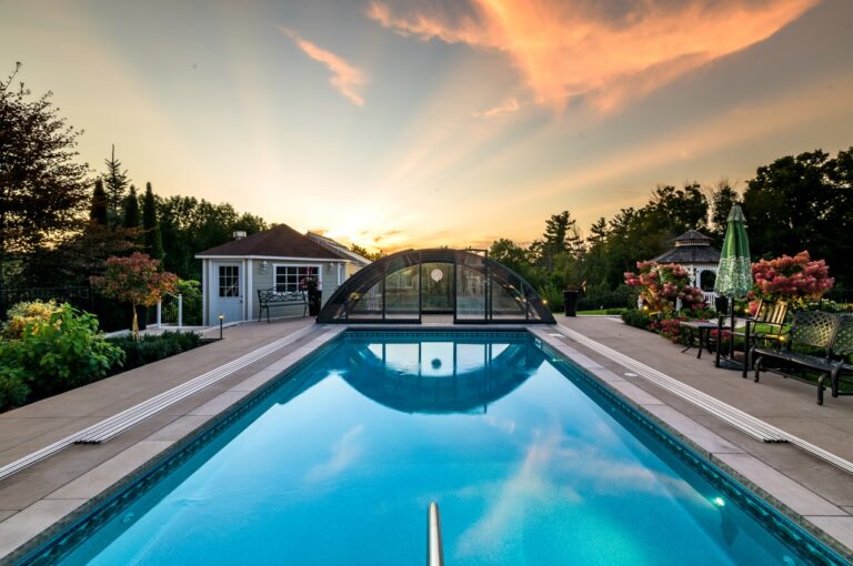 Rectangular outdoor pool with retracted pool cover and patio furniture